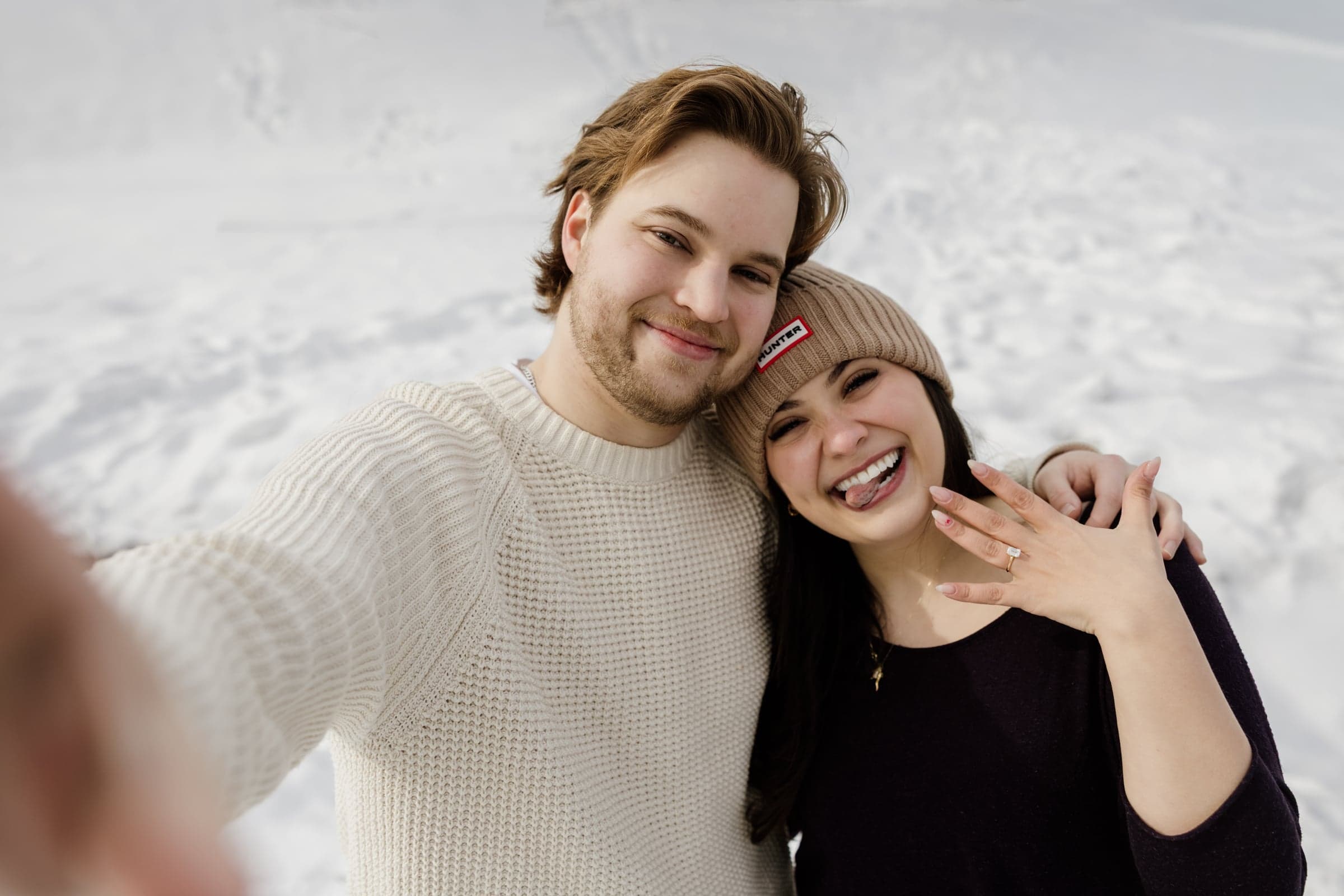 Victoria and Christoph laughing together in the snow, showing her engagement ring